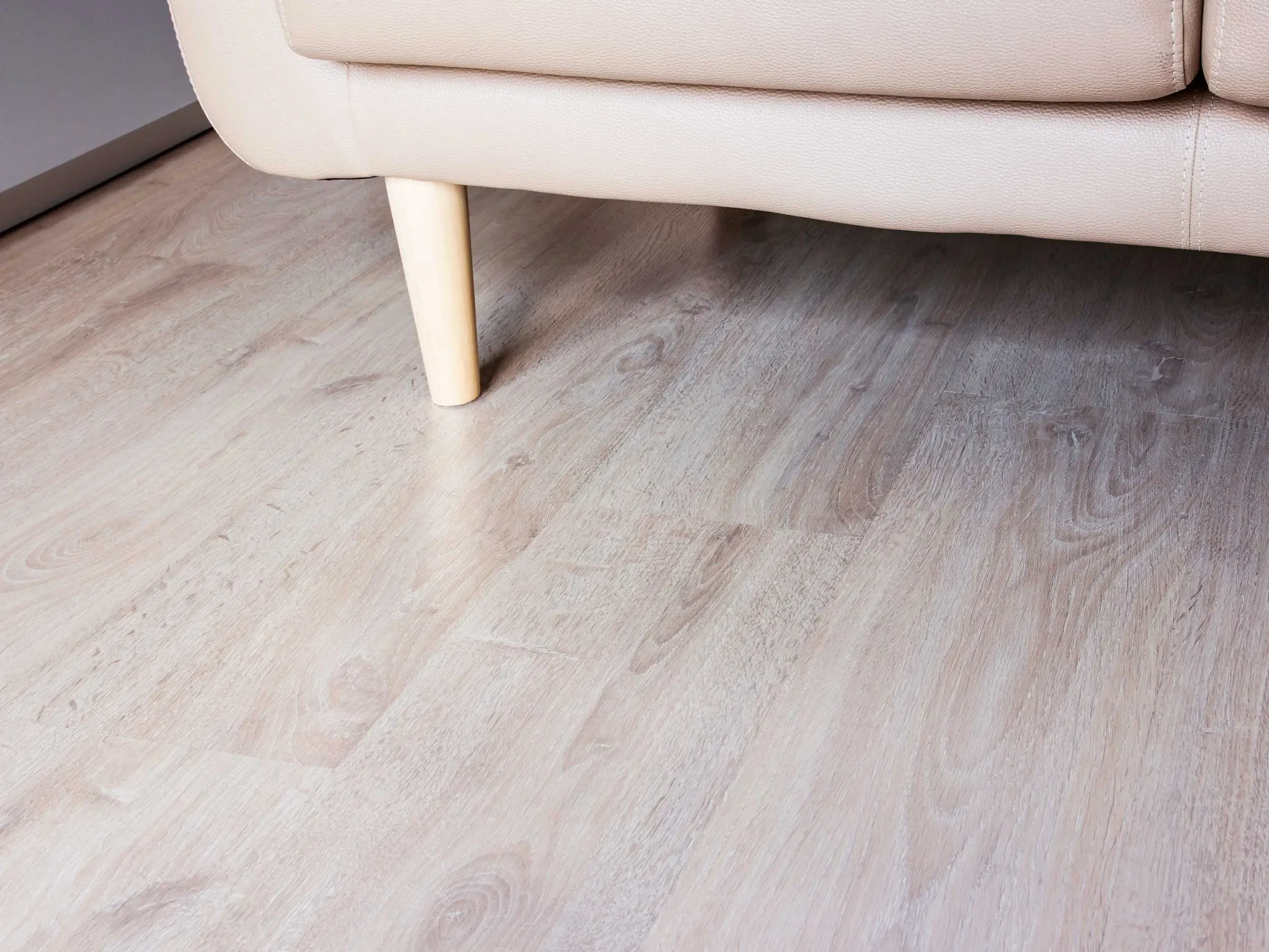 Smooth laminate floor in the living room with part of sofa in background.