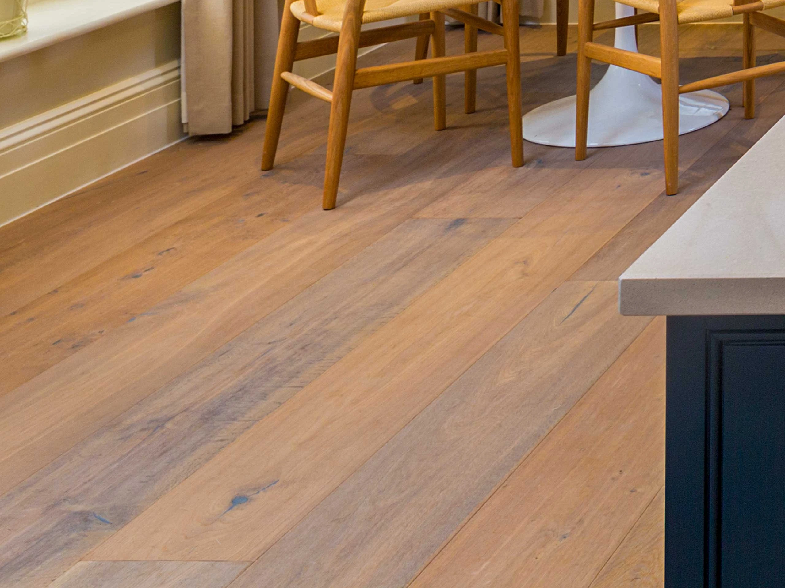 Close up of engineered wood in a kitchen with a dining table and chairs.