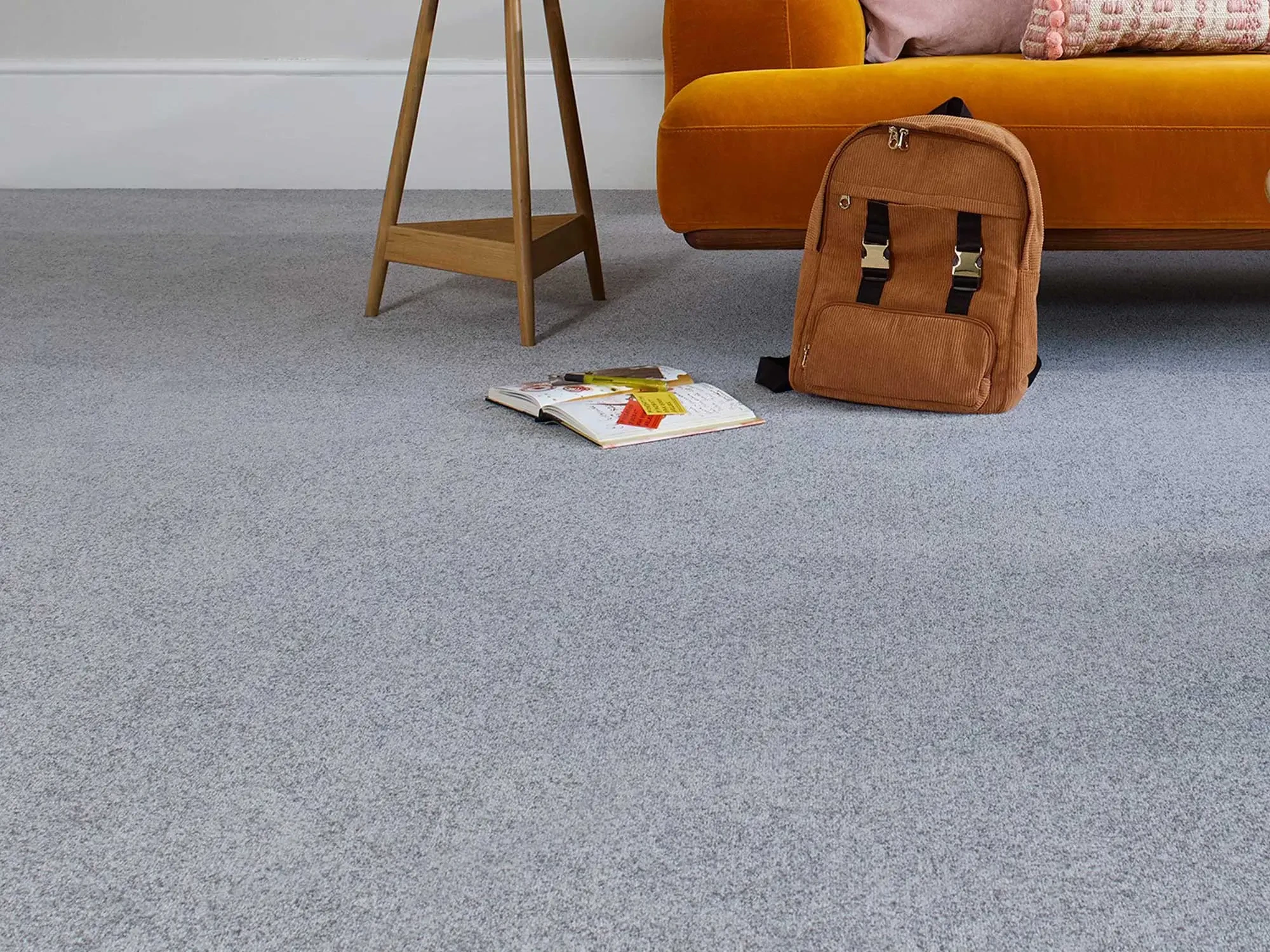 Grey twist carpet in a living room with a brown rucksack in the background.