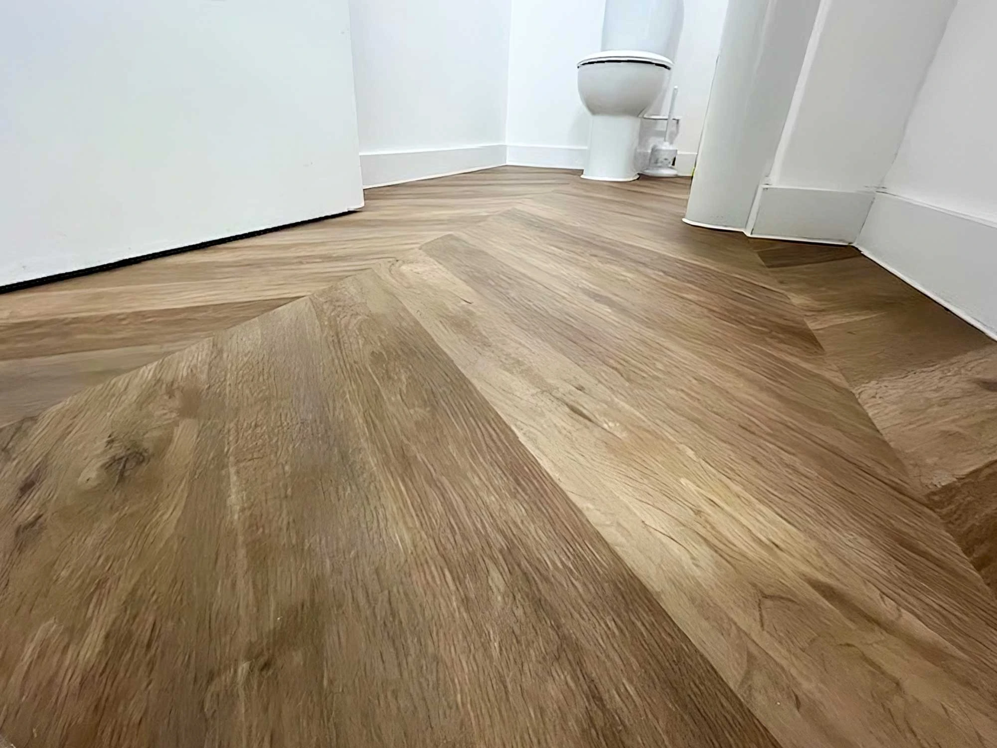 Close up view of wood effect sheet vinyl laid out in a toilet area.